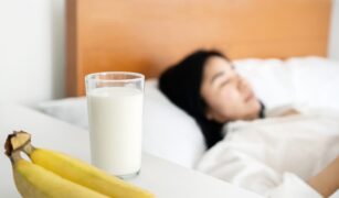 Tanara care doarme avand pe noptiera banane si un pahar de lapte