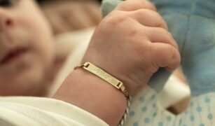 Bebelus poarta o bratara aurie pe care e inscriptionat numele lui