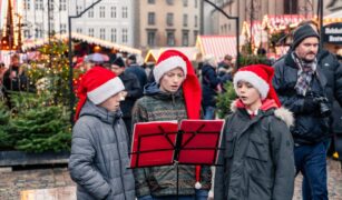 Trei copii canta colinde in aer liber