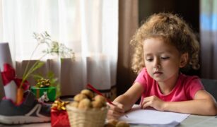 O fetiță îi scrie o scrisoare lui Moș Nicolae