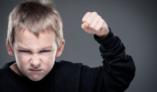 un băiețel furios, amenință cu pumnul ridicat