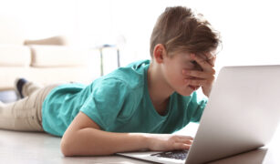 copil care se uita la laptop si pune mana la ochi