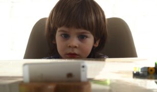 copil la masă cu ochii în smartphone